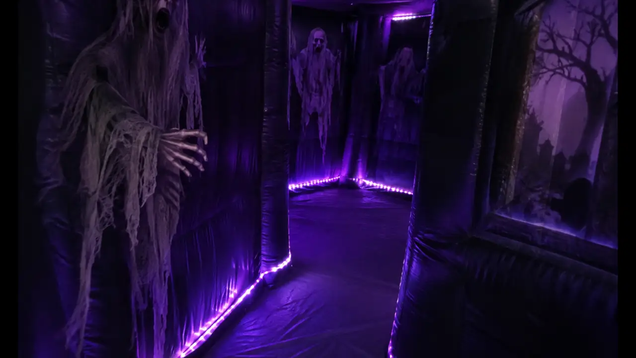 Interior oscuro de laberinto de casa embrujada inflable con iluminación LED morada
